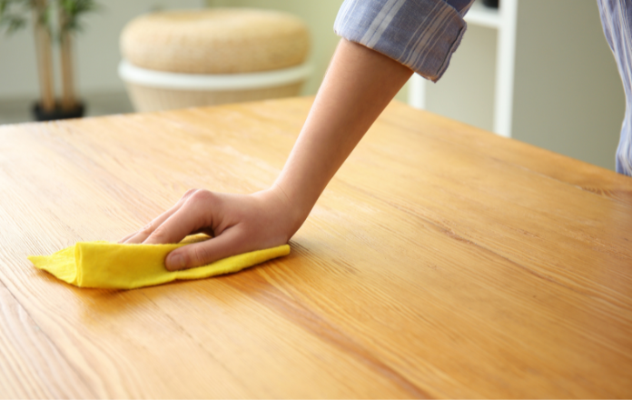 Hand cleaning a Pine Wood table using a damp soft cloth