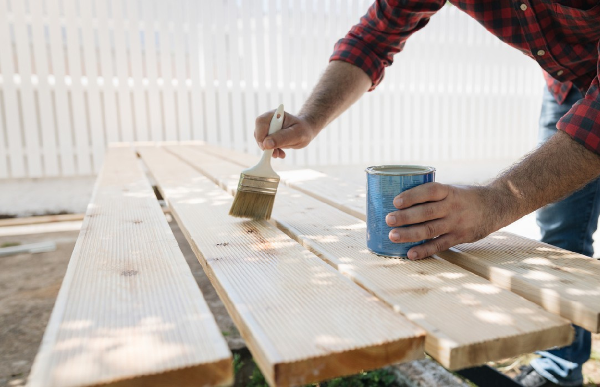 Person applying waterproofing product onto wooden planks