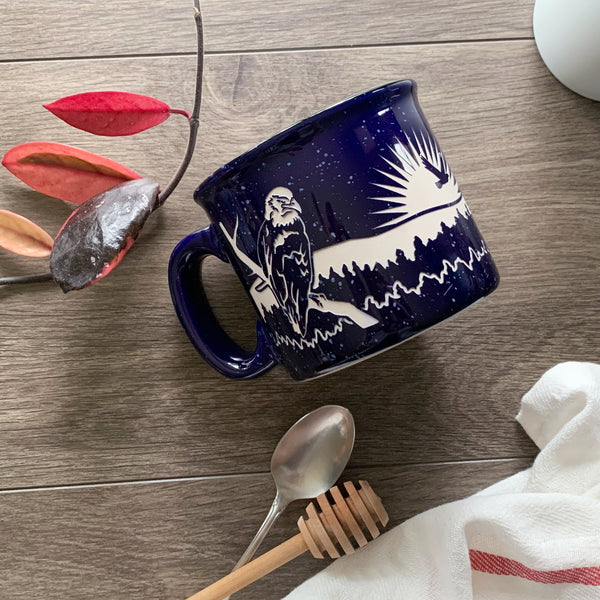Bald Eagle Mug in Camp Navy Blue, resting on a wooden table decorated in subtle patriotic colors