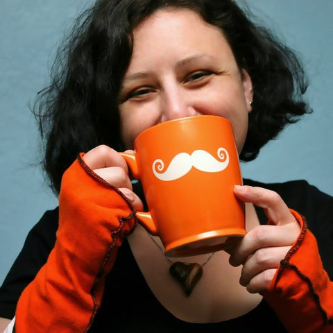 orange mustache mug held up to a woman's face