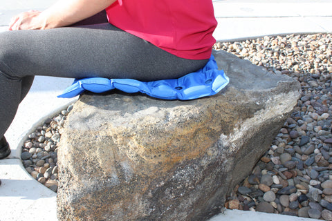 Woman using an EverRelief Air Inflatable Seat cushion to rest comfortably on a rock during her walk.