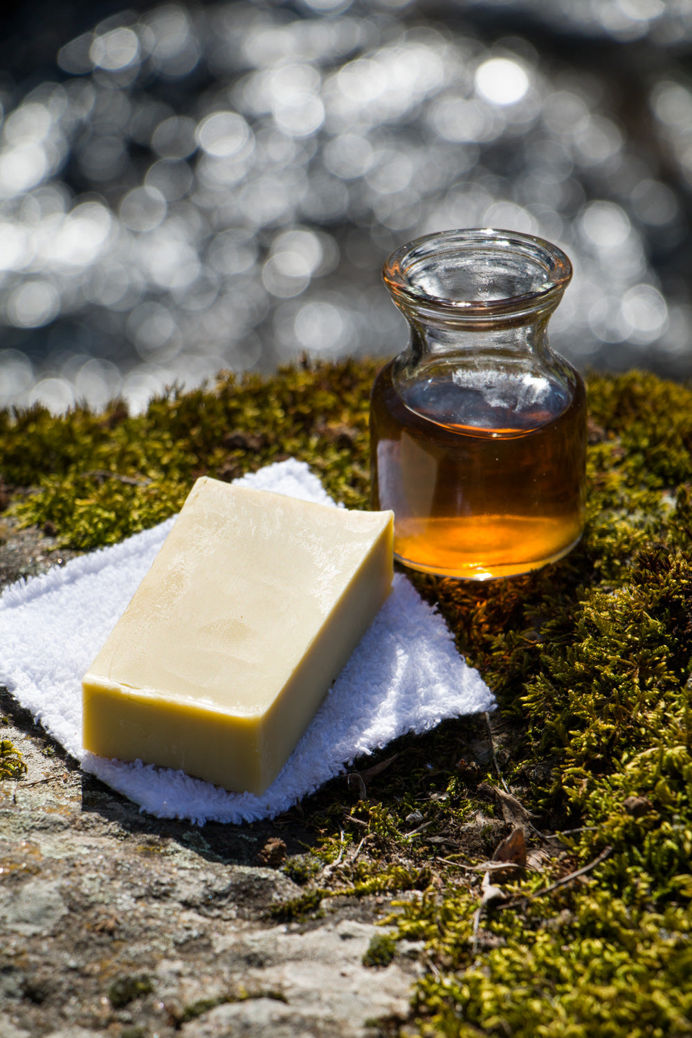 A natural Rosehip Soap on top of a white towel and a glass jar of chamomile.