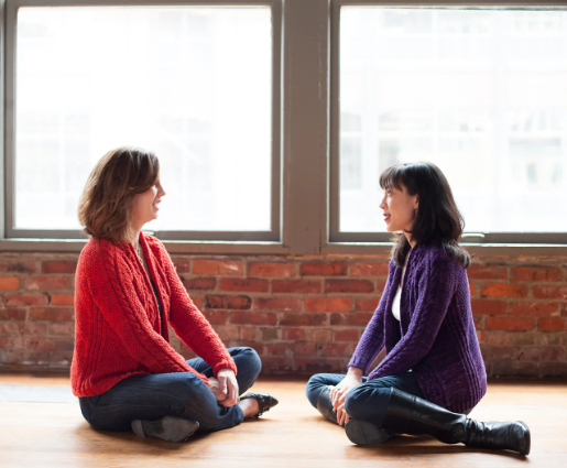 Two women wearing hand knitted cardigan sweaters