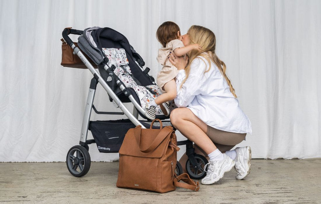 mum getting her bub from pram and Emmy Backpack bag at the floor