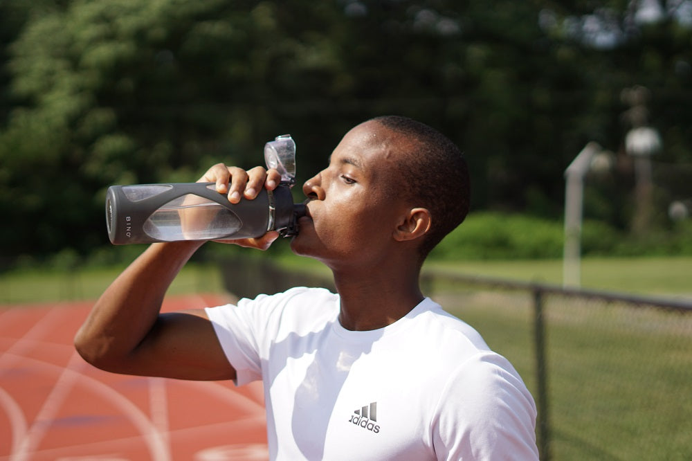 Man drinking water on a sports track.