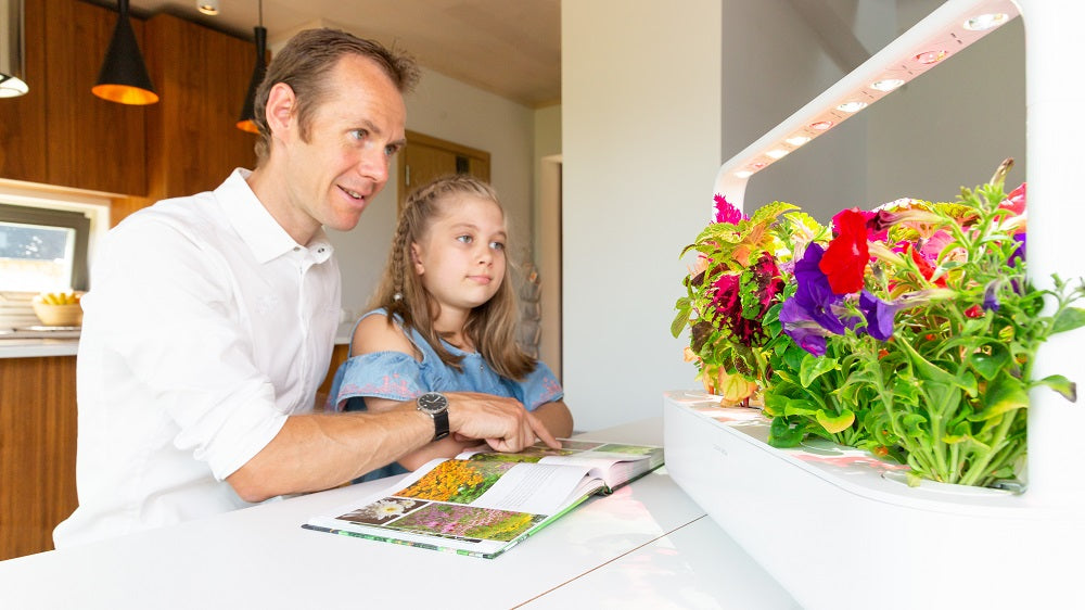 Father and daughter observing plants growing in a smart garden.