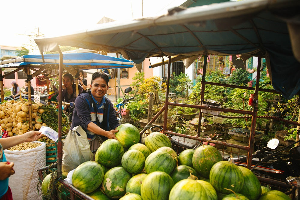 Smiling man selling watermelons at the market.