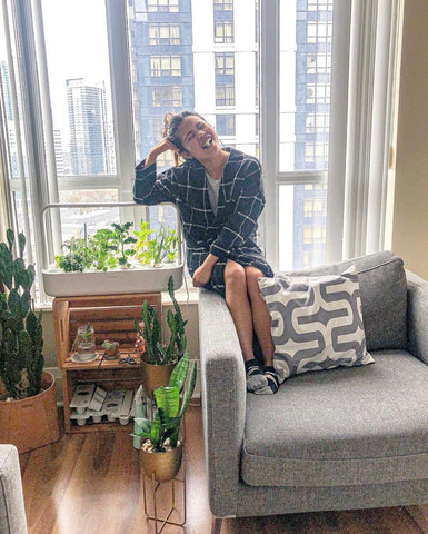 Girl sitting on sofa beside a Click and Grow smart garden.