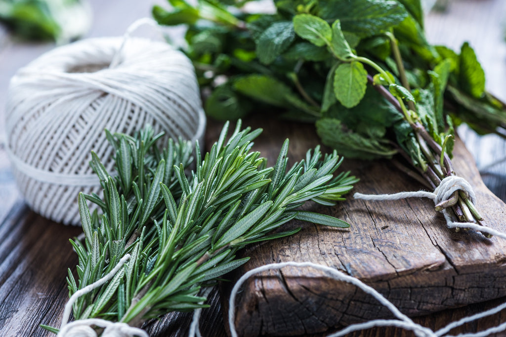 Sprig of herbs neatly arranged on a wooden board and table.