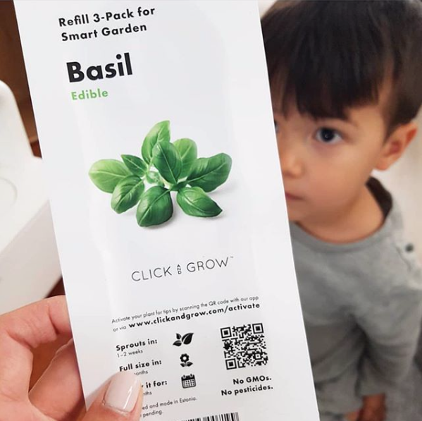 boy looking at caregiver holding a pack of click & grow basil plant pods
