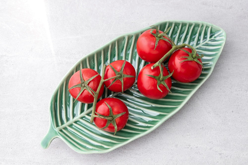 Mini tomatoes on a green, leaf-shaped plate.
