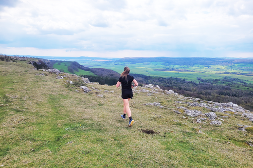 Female runner on Scout Scar running towards scenic views of Morecambe Bay estuary