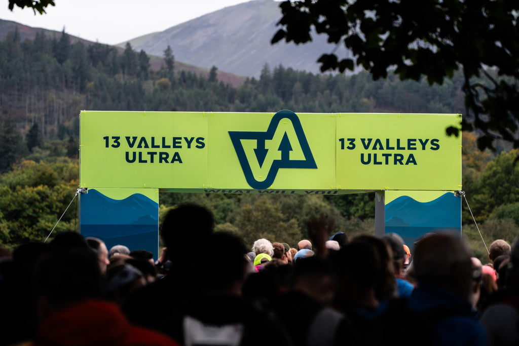 A crowd standing beneath a 13 Valleys branded archway ahead of the event start in Keswick's Crow Park