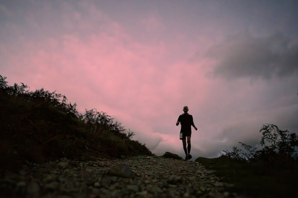 A runner starts to descend a Lakeland trail at dusk during the 13 Valleys Ultra event