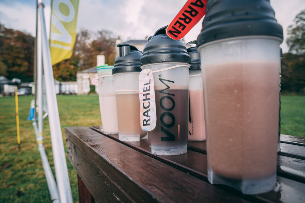 Protein shakers with VOOM Rapid Recovery set out on a table at the event finish area