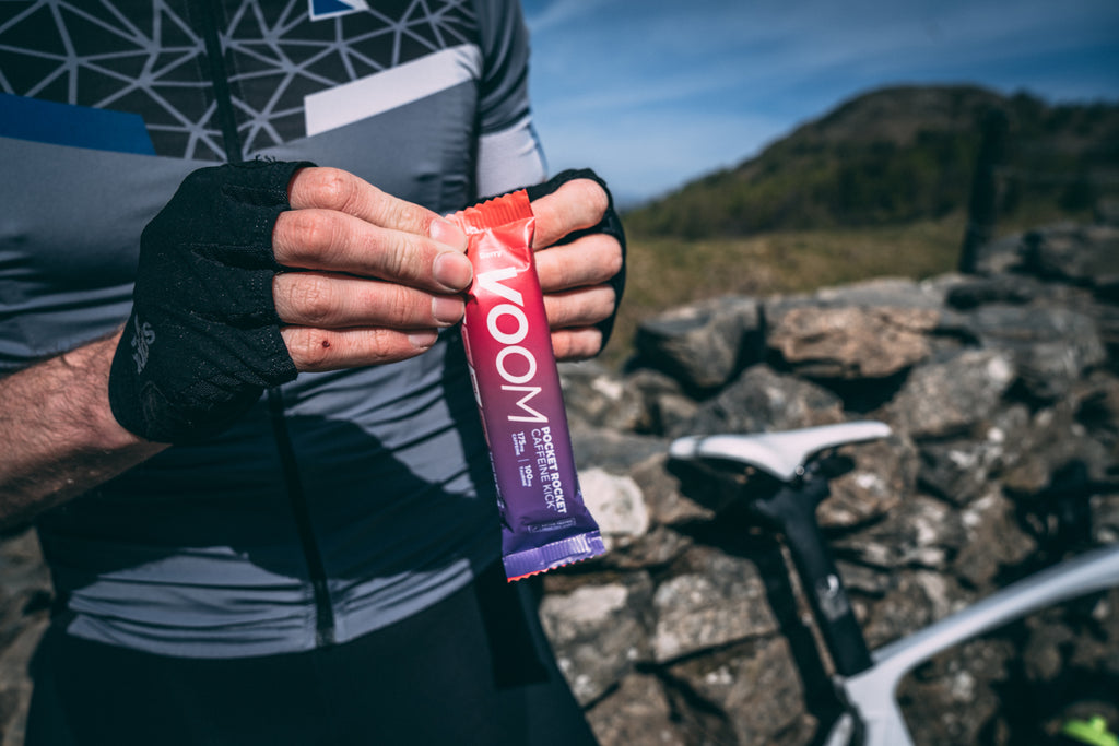 A VOOM Pocket Rocket Caffeine Kick held in a cyclists hands as he opens the wrapper
