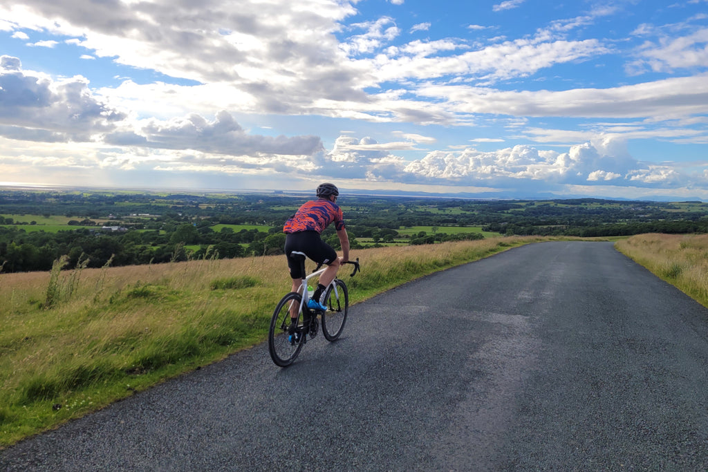 Road cycling near Lancaster on Harrisend Fell, Lancashire, with views towards Morecambe Bay and the Lake District mountains
