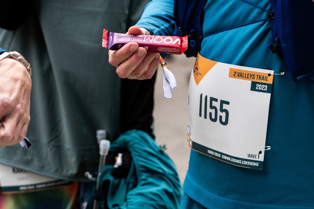 An ultra runner holds a Caffeine Kick Pocket Rocket, about to use it to get a carb and caffeine lift.