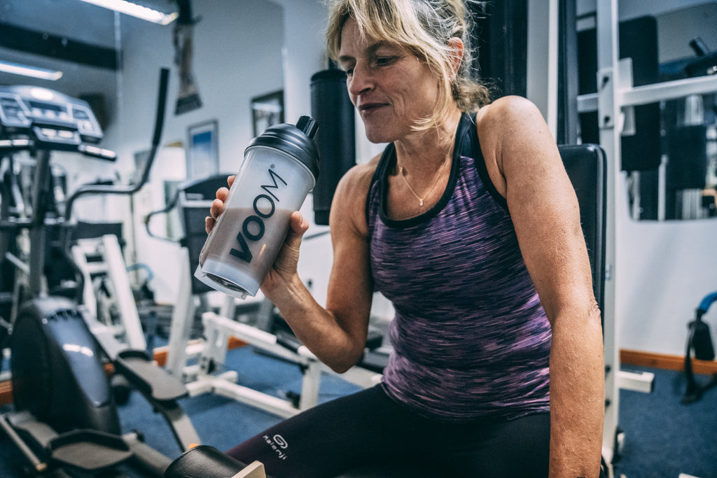 A woman drinks a protein recovery shake to recover after a workout