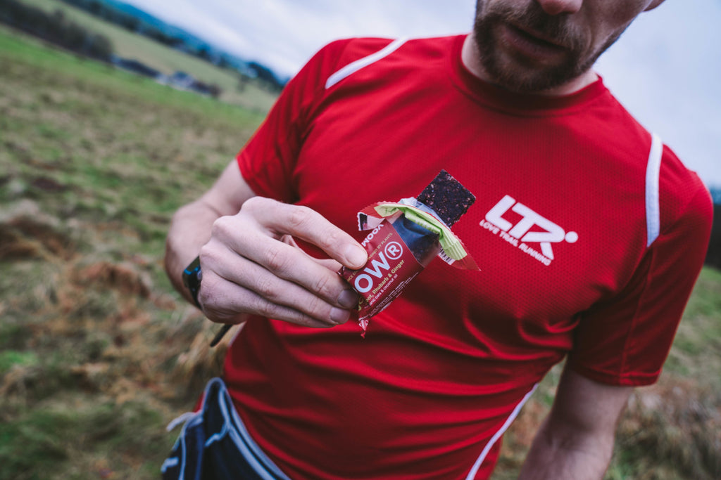 An ultra runer holding an open ginger energy bar with fuel on the go having just taken a bite