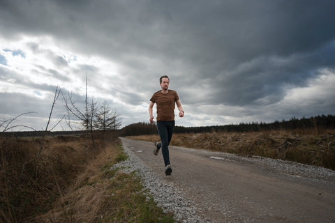 A runner heads along a gravel road under a dark, stormy sky