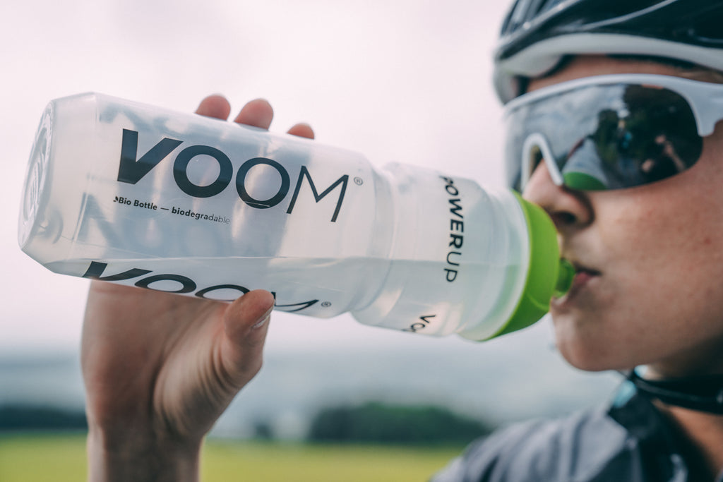 A female cyclist drinks VOOM Electrolyte drink from a bottle to improve hydration