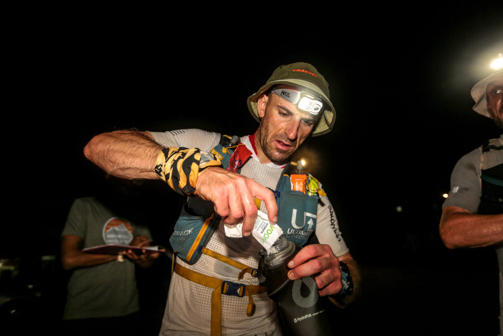 An ultra runner refills a soft flask during hot conditions with VOOM electrolyte drink