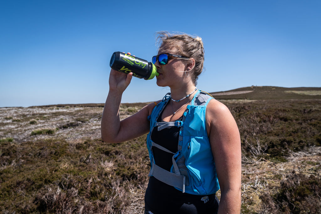 A female runner uses a sports hydration drink to improve hydration on a hot day