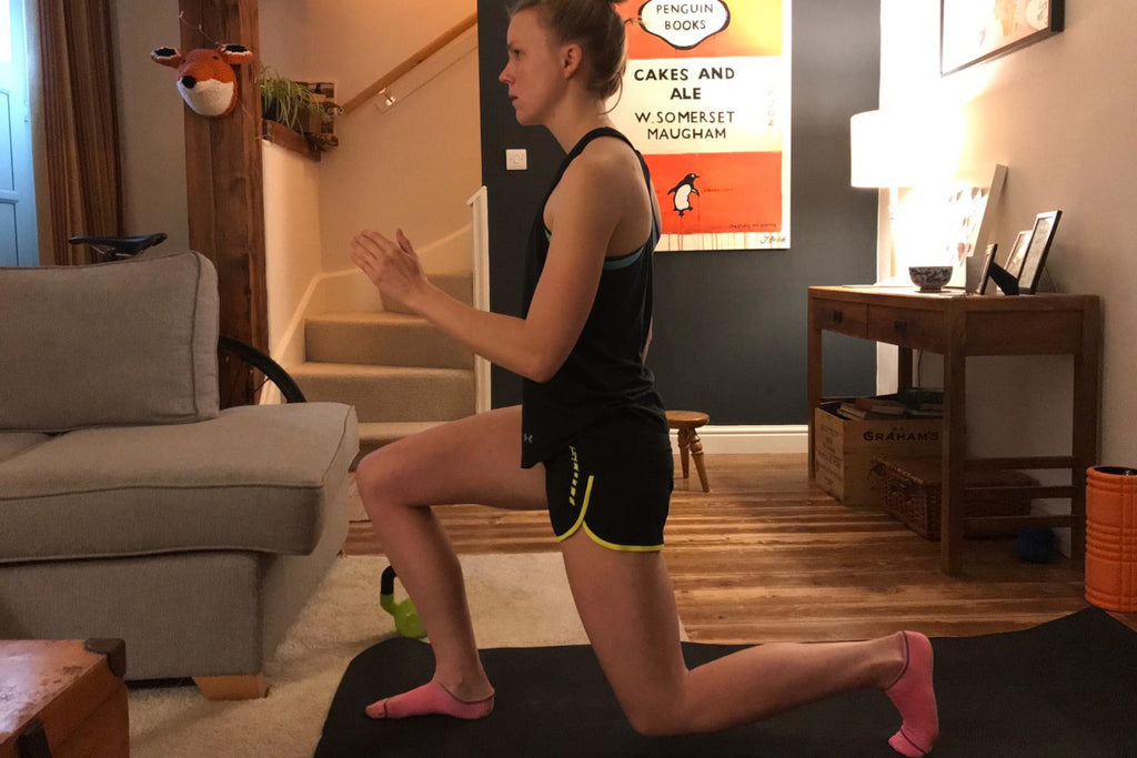 A female runner does a lunge on a training mat in the living room