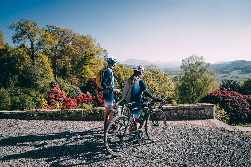 2 Cyclists enjoy the view from Muncaster Castle on a sunny morning, looking across the Esk valley in the Lake District