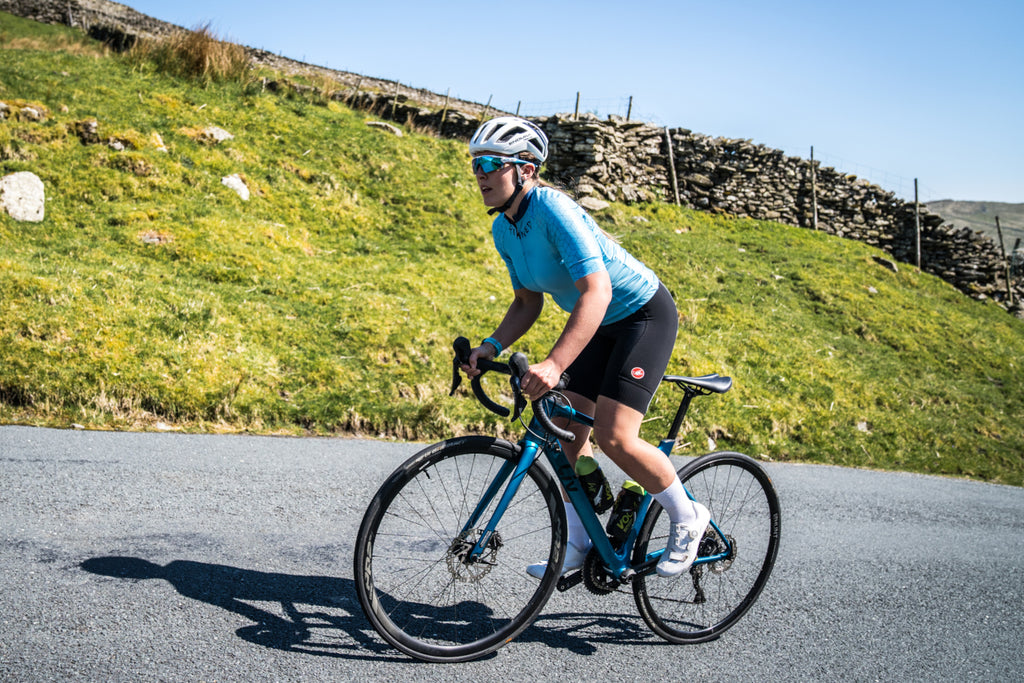 A female cyclist sprinting uphill during a ride up The Struggle near Ambleside, England.