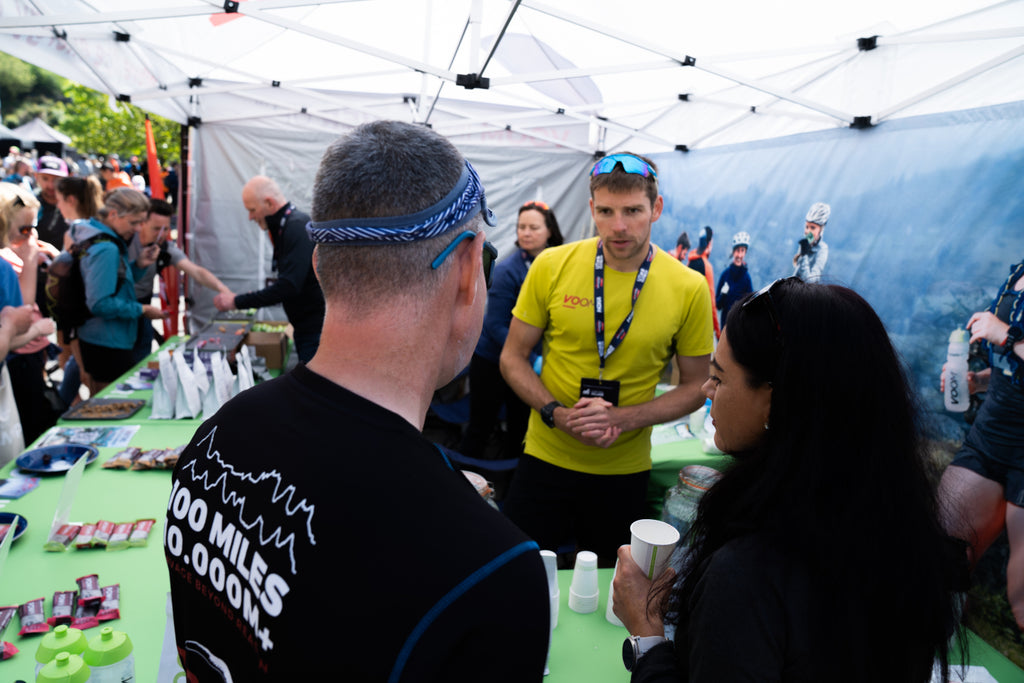 Two runners talk to a team VOOM staff member at a running exhibition