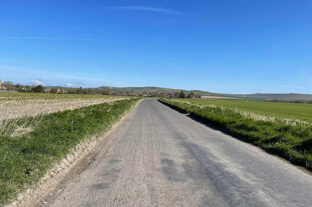 A flat, open countryside road under a very blue sky.