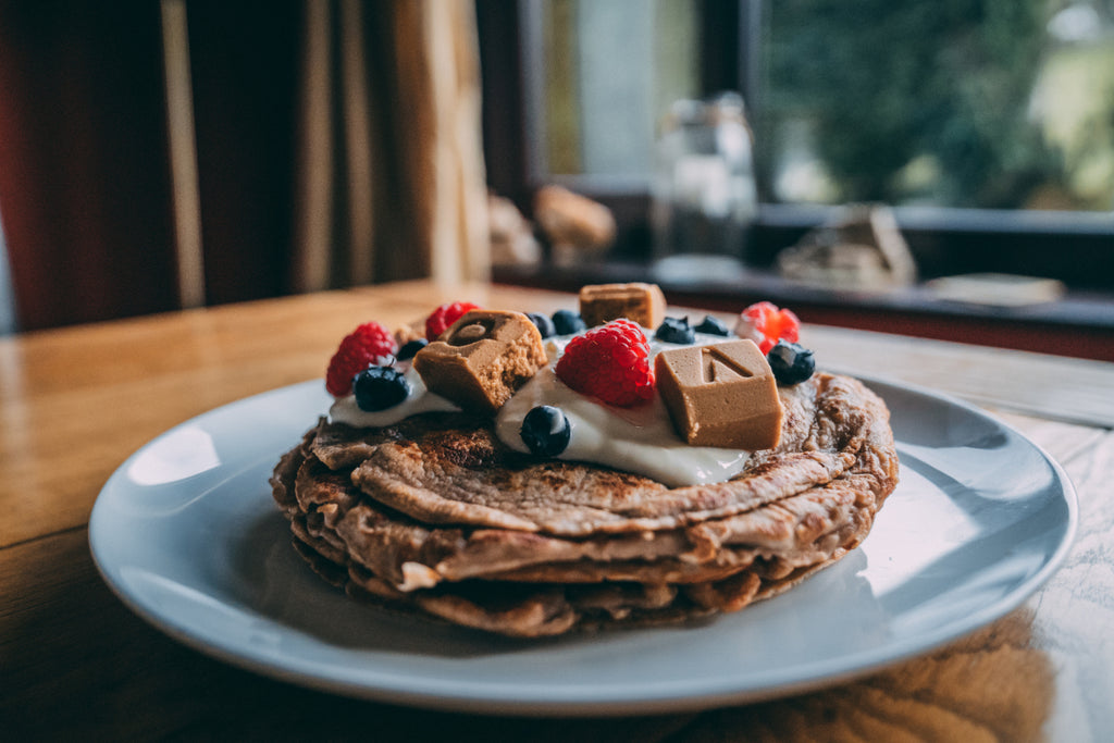 A stack of protein pancakes topped with VOOM RecoverFudge and berries