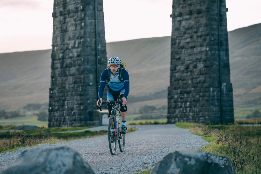 A gravel rider cycles beneath the huge stone arches of the Ribblehead viaduct in the Yorkshire Dales National Parl