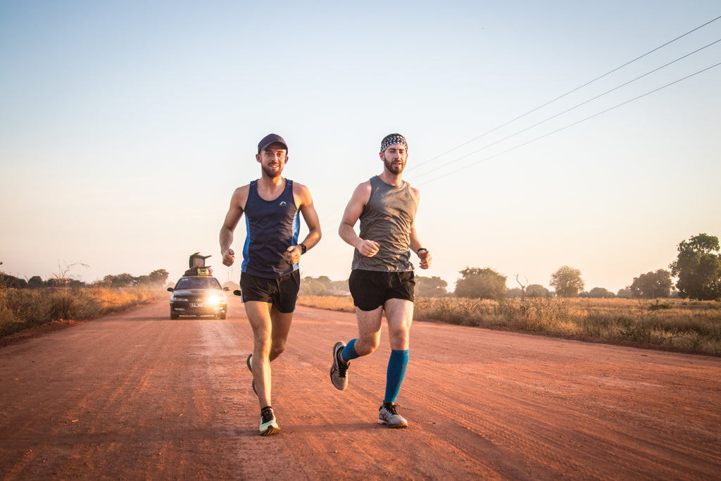 Two runners stride along a dirt road side by side