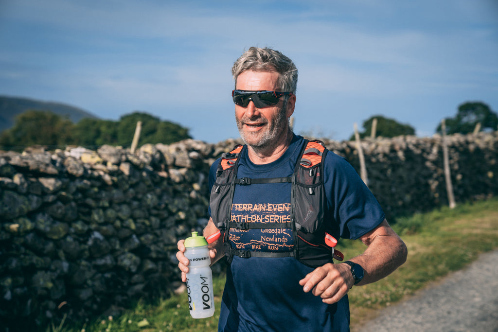 A male runner carrying an electrolyte drink in a bottle during a running event