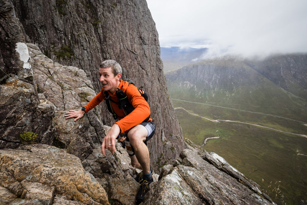 A male skyrunner scrambles up steep rock int he Scottish Highlands during Skyline Scotland 2022