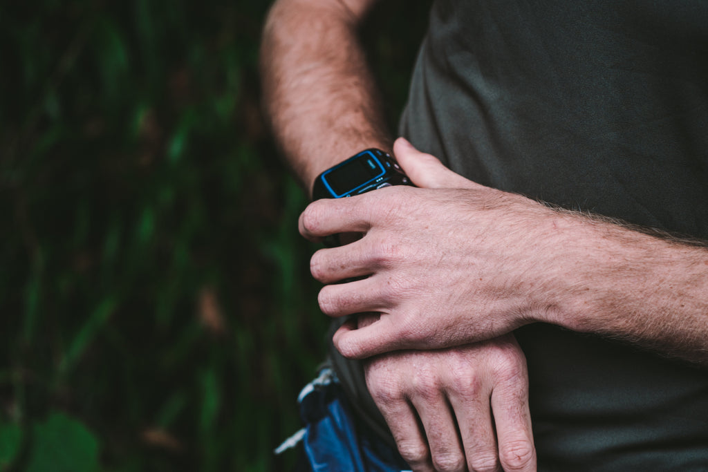 A runners hand presing the start button on his Garmin watch before running