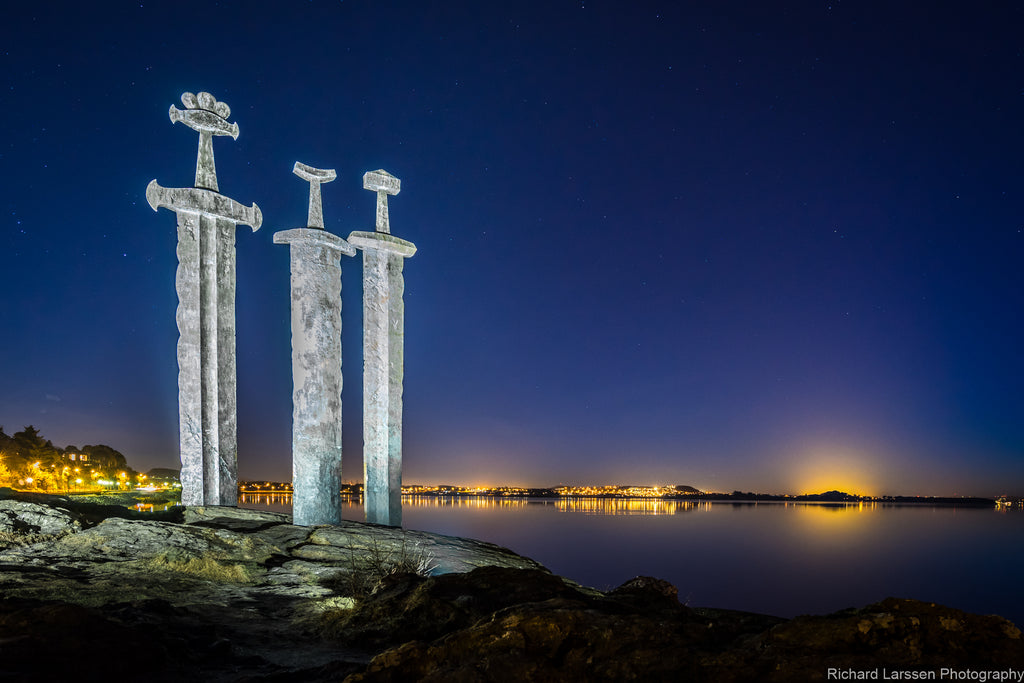 The impressive 'three swords' site at Stavanger, Norway at dusk with the glow of the town's lights in the background