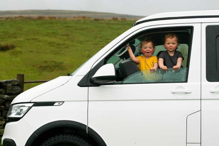 Twin children up the front of a camper van