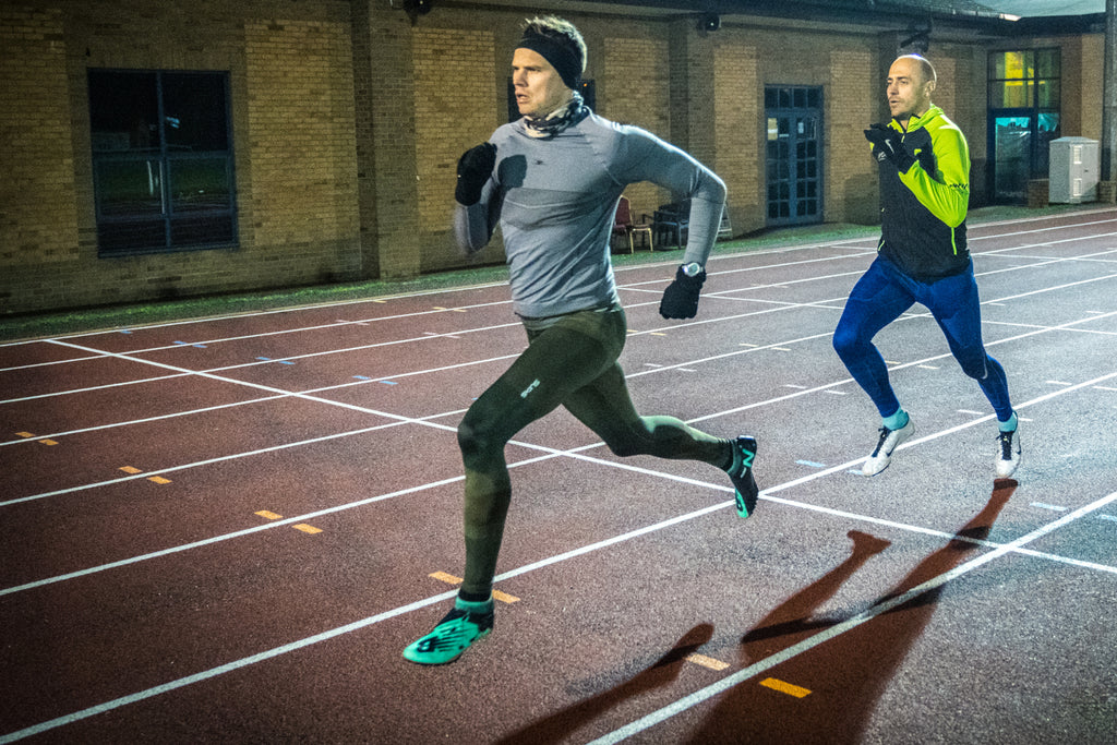 Two male track runners push to the finish line during a 3000m time trial during a training session