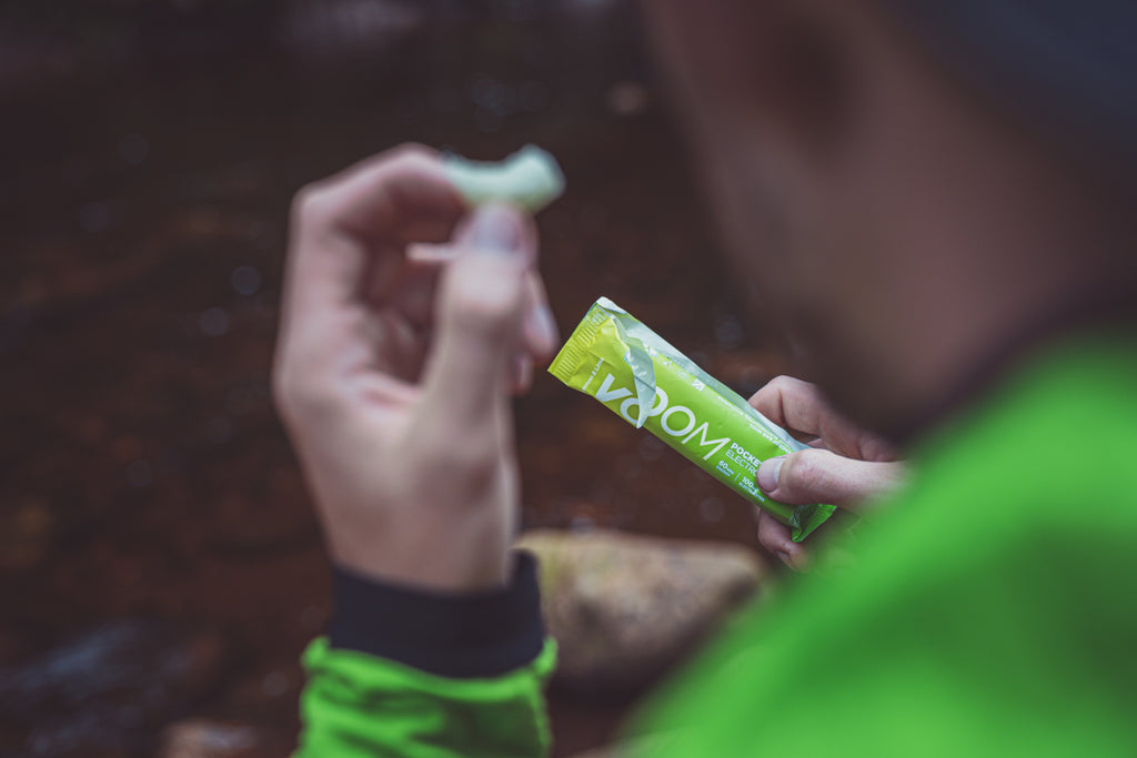 A close up of a hand holding one piece of a VOOM Pocket Rocket energy bar for running