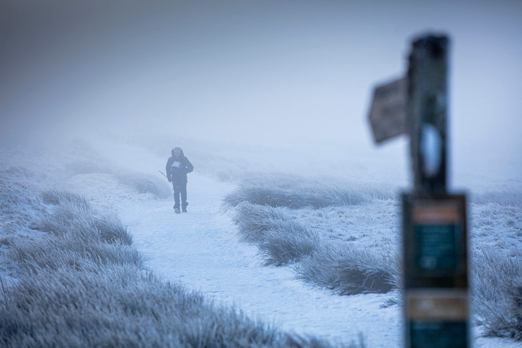A lone figure runs along a snowy track during the winter spine challenger north race.