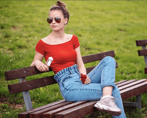 femme assise sur un banc de parc en été et vapotant