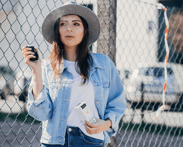 femme debout devant la clôture vaping