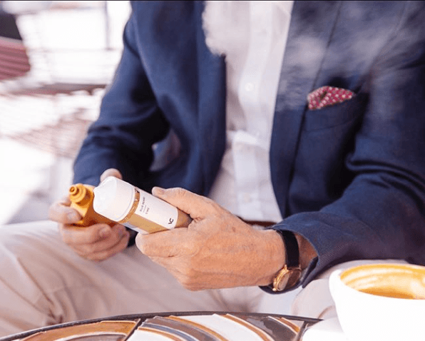 homme tenant un stylo vape et un e-liquide