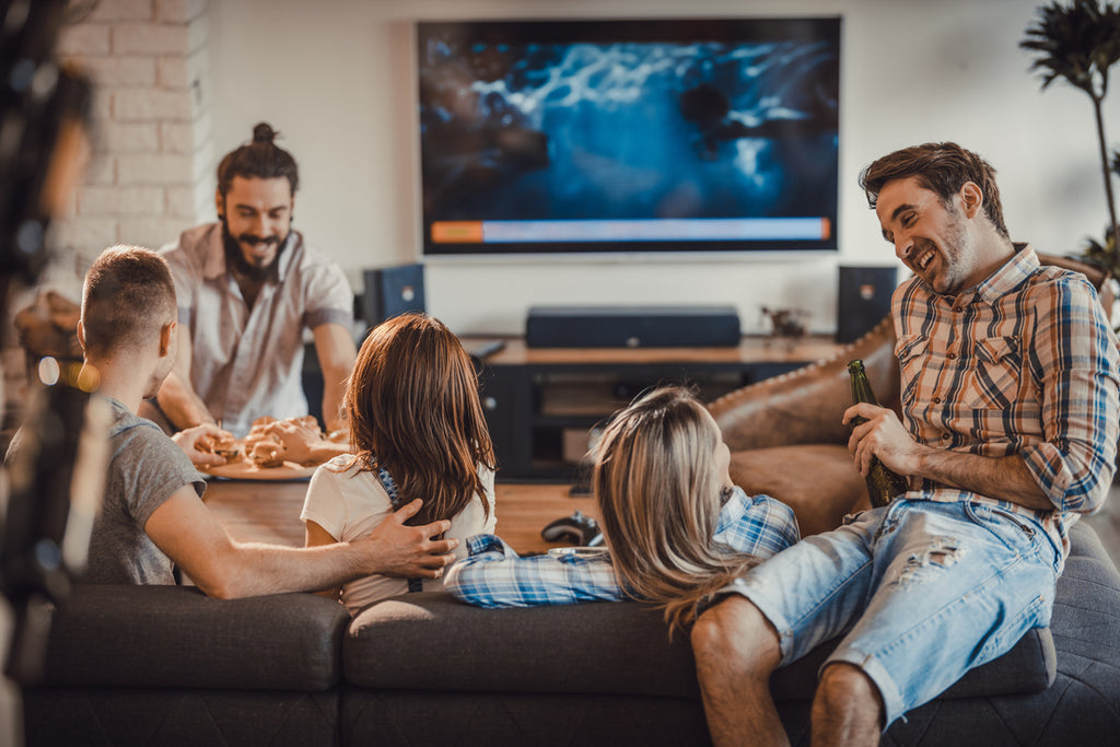 group of friends at a house party with tv on in background