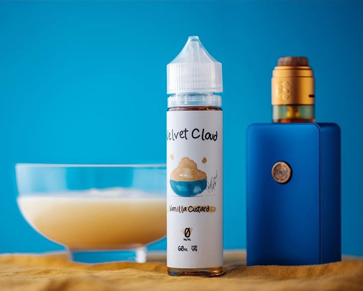 a picture of a vaping mod and velvet cloud vainlla custard e-liquid next to a bowl of vanilla pudding