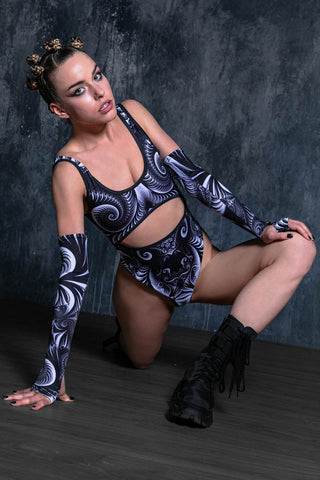 A woman wearing black rave bodysuit with long sleeves and classic goth boots.